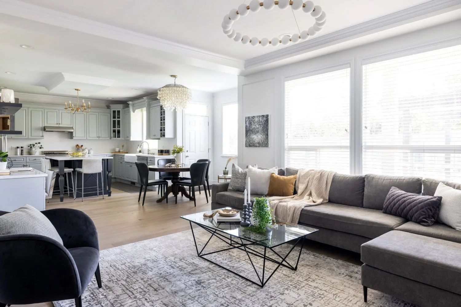 A renovated family room and kitchen in South Surrey, with a grey sectional and a pearl chandelier.