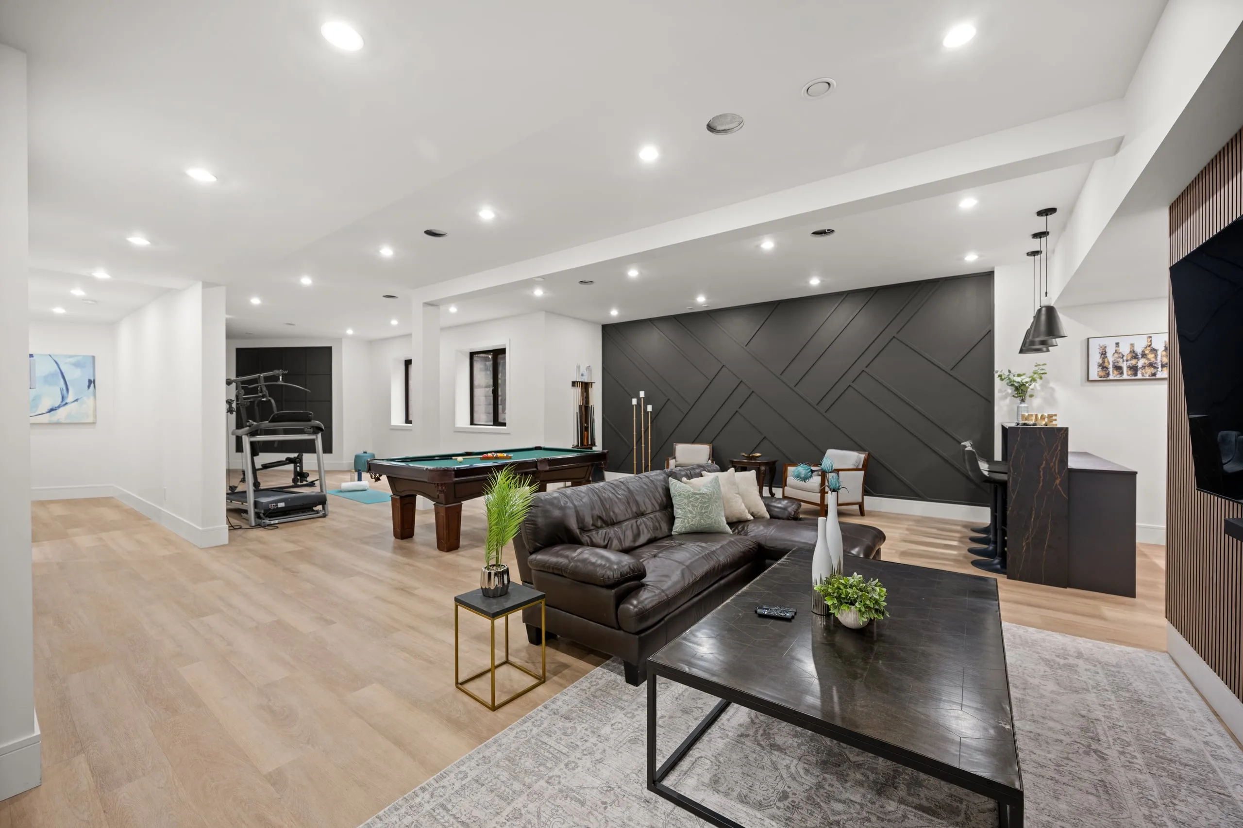 The lower-floor games room, with a pool table, a lounge and the navy feature wall.