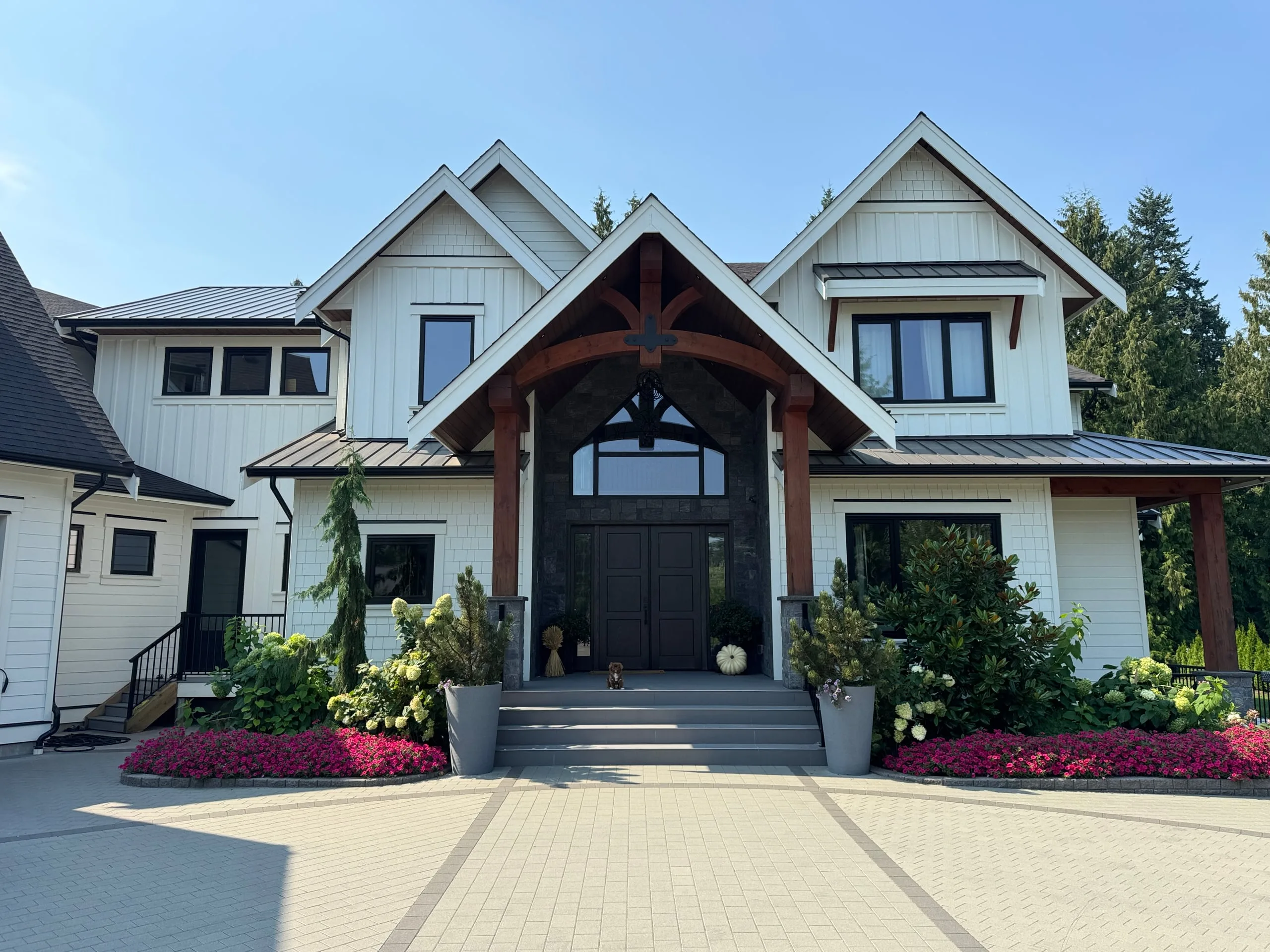 The front of the Modern Country Estate, a custom home ProStyle built in Langley, with a heavy-timber gable porch over double doors.