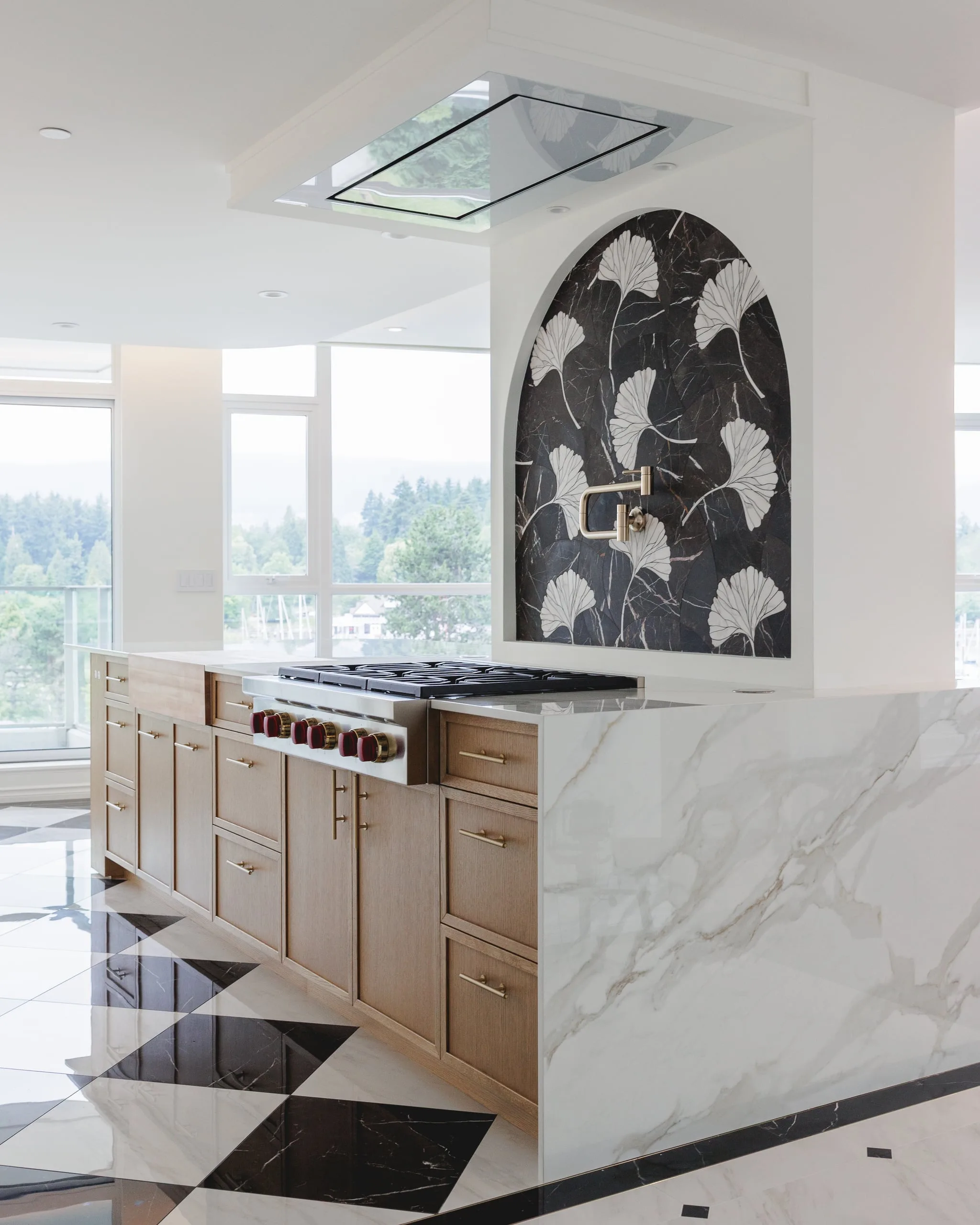 The kitchen island and range under a black-and-white ginkgo mosaic arch, with the city beyond.