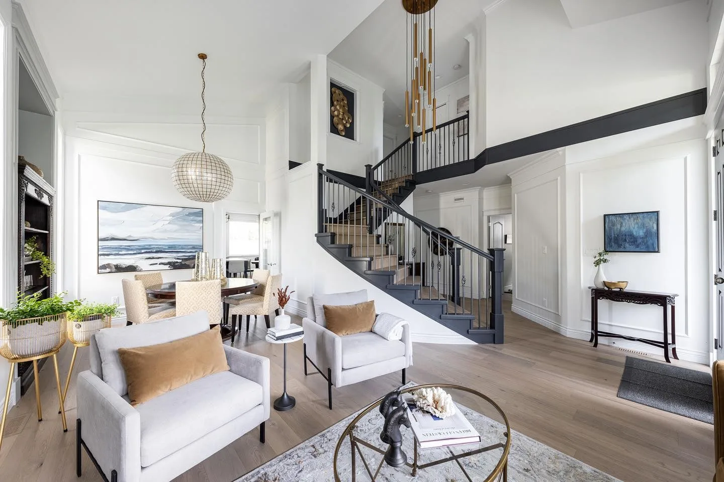 The living area of the Modern Classic Residence in South Surrey, looking toward a curved staircase with a black railing under a brass pendant.