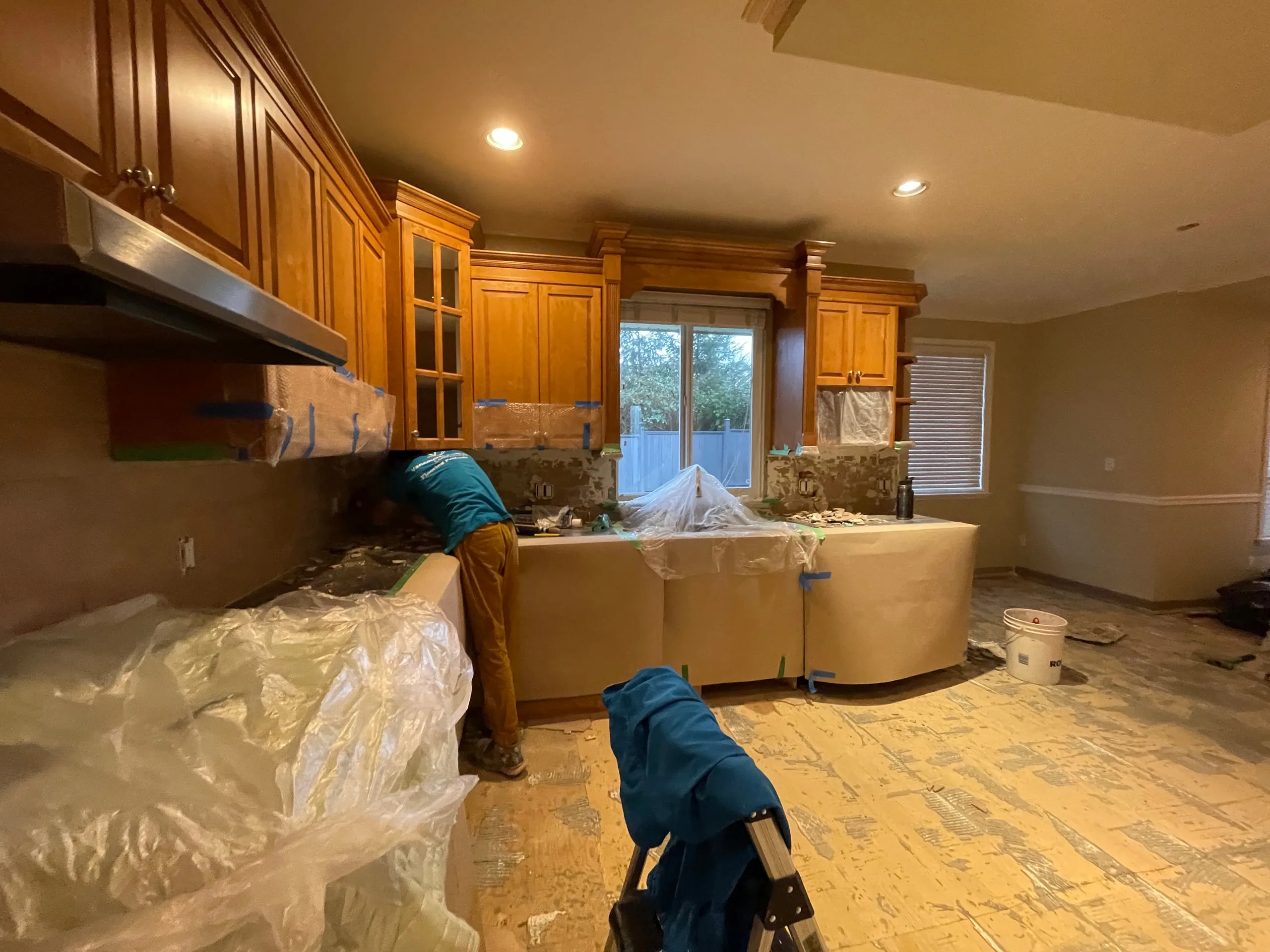 The kitchen of the Modern Classic Residence during the first phase, its cabinets and counters wrapped in plastic and paper while the work goes on.