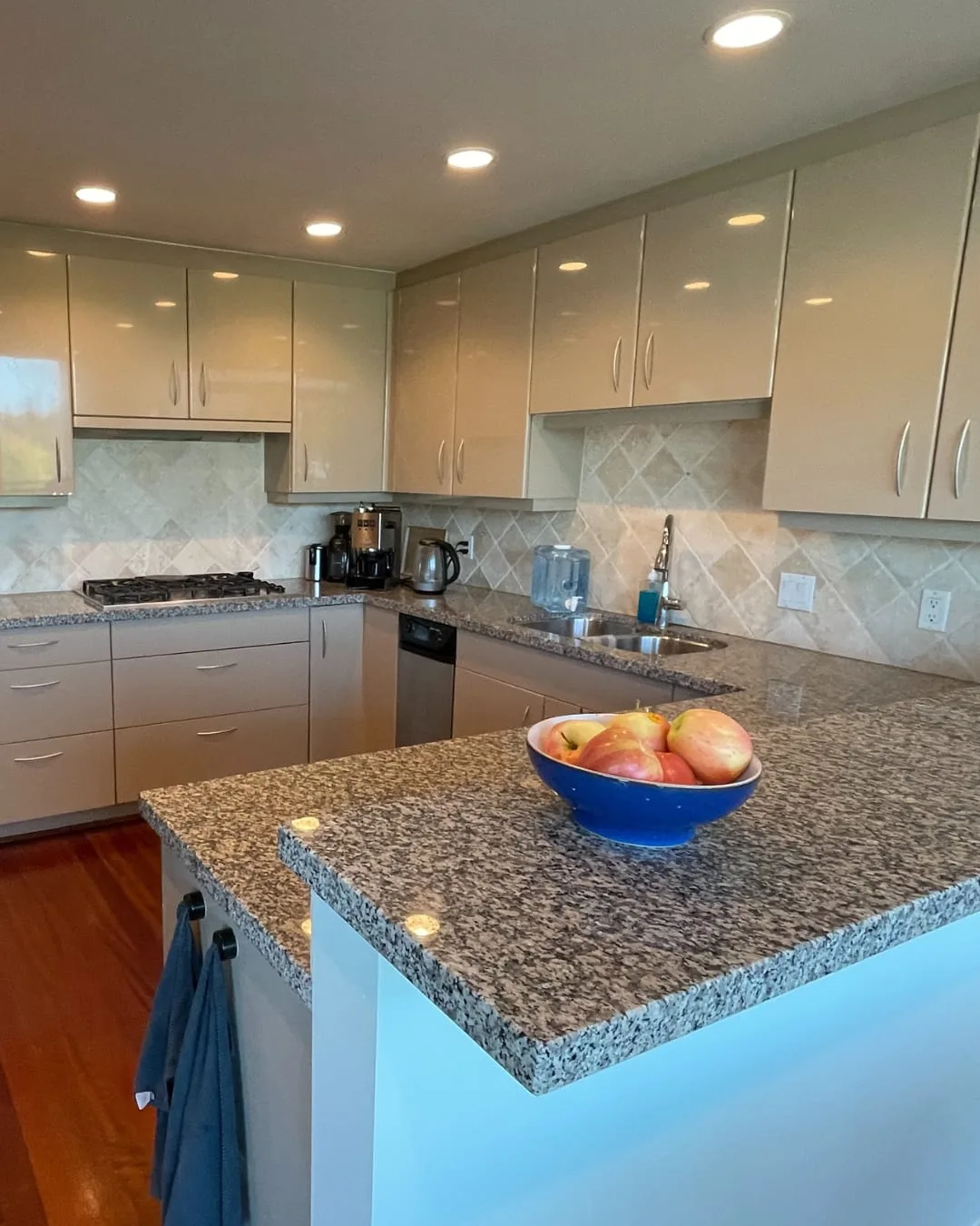 Before: the original kitchen, with beige gloss cabinets, a granite peninsula and cherry floors.